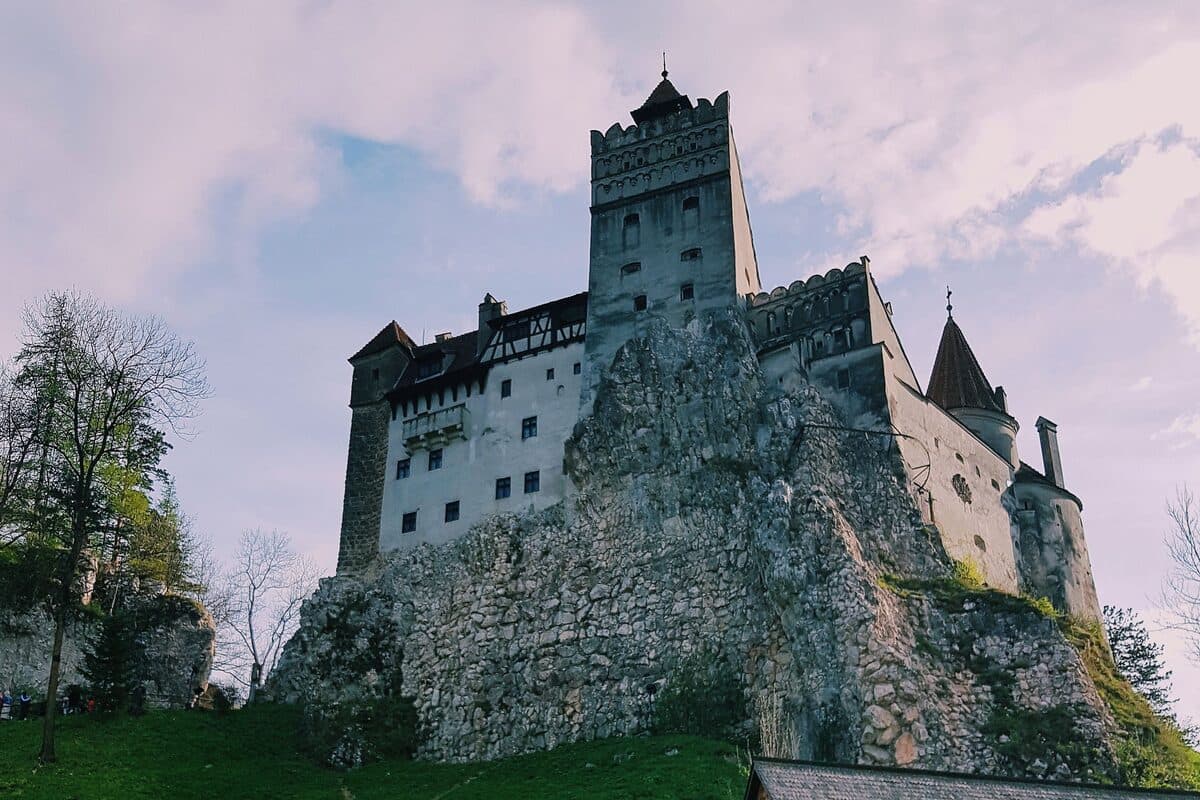 Castelul Bran pe stânca lui, cu o casă tradițională din lemn în prim-plan