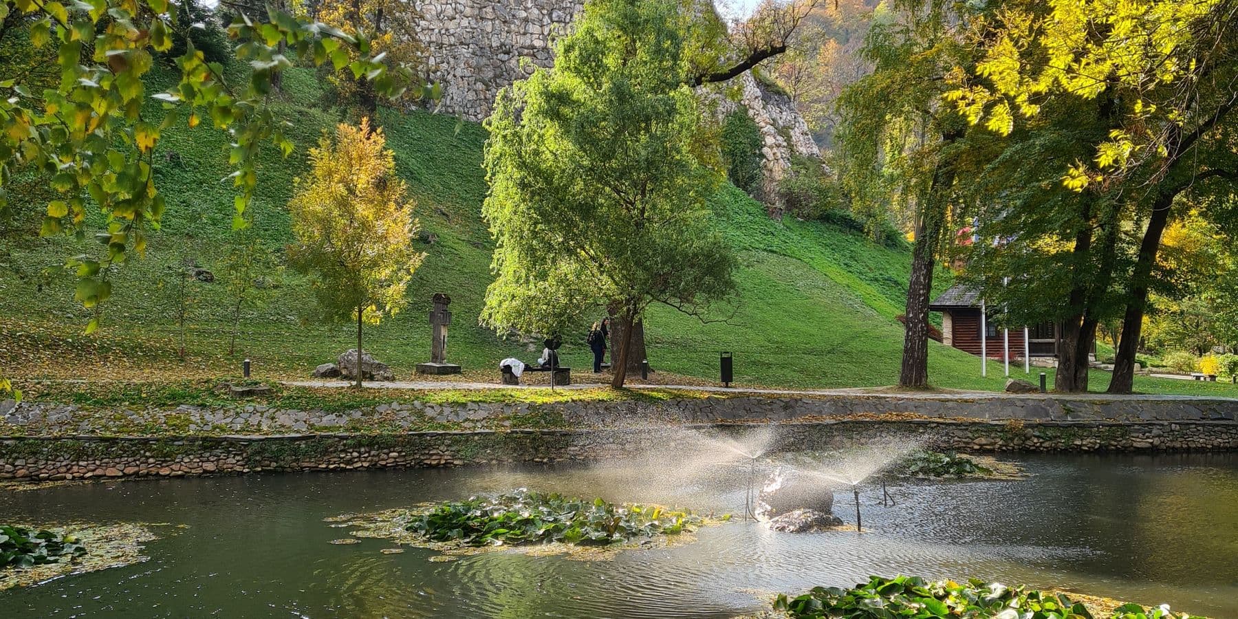 Bran Castle above the pond in the park below its rock, in autumn